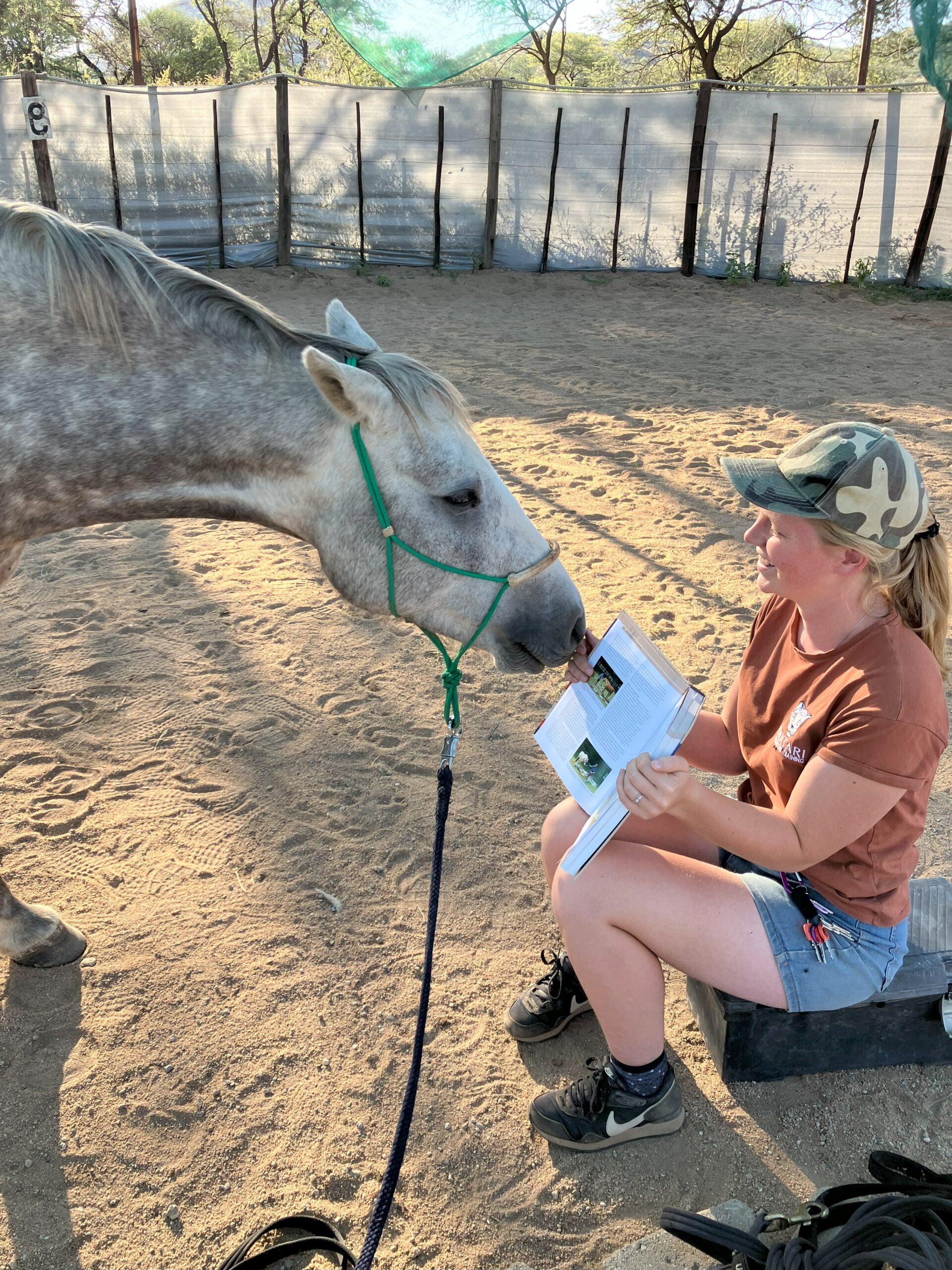 Aline du Plessis leest een boek bij een paard in Namibië.